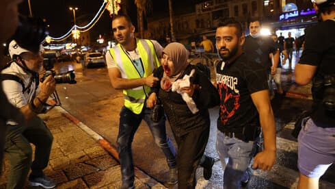Dos hombres ayudan a una palestina que resultó herida durante los enfrentamientos. (Alex Kolomoisky) Dos hombres ayudan a una palestina que resultó herida durante los enfrentamientos.