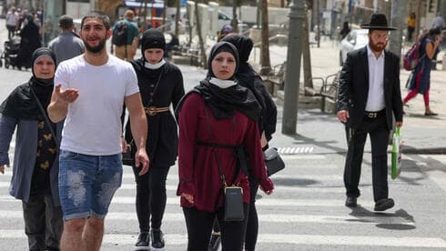 Israelíes caminan por Jerusalem sin cubrirse el rostro con mascarillas. 