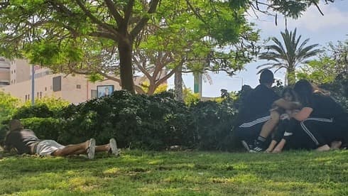 Israelíes se cubren mientras suenan las sirenas de alerta en Ashkelon.