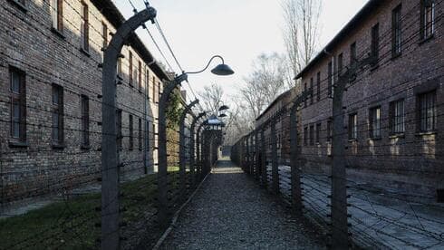 Un camino que conduce a una torre de observación y seguridad entre lo que fueron las vallas eléctricas de alambre de espino dentro del antiguo campo de exterminio nazi de Auschwitz I en Oswiecim, Polonia.
