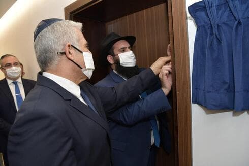 Lapid coloca la mezuzá en la embajada israelí inaugurada en Abu Dhabi.
