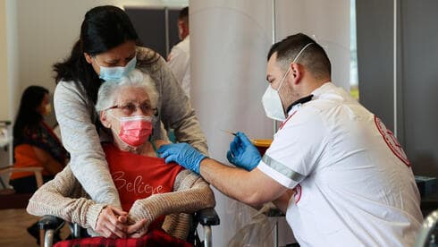Una adulta mayor de una residencia de ancianos en Netanya sostiene la mano de su cuidador mientras recibe la vacuna contra el coronavirus. (Reuters) Una adulta mayor de una residencia de ancianos en Netanya sostiene la mano de su cuidador mientras recibe la vacuna contra el coronavirus.