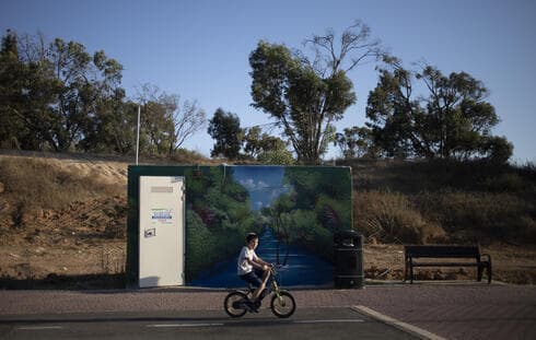 Un niño pasea en bicicleta frente a un refugio antiaéreo de hormigón pintado colocado en un parque público en Sderot, Israel. 