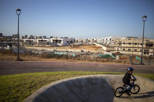 Un niño monta sus bicicletas en un parque público con vista a un sitio en construcción en Sderot, Israel. 