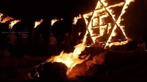 Una estrella de David de madera con una cruz esvástica en el centro en llamas tras ser prendida fuego por manifestantes palestinos cerca del asentamiento Eviatar, en Cisjordania. Una estrella de David de madera con una cruz esvástica en el centro en llamas tras ser prendida fuego por manifestantes palestinos en Cisjordania.