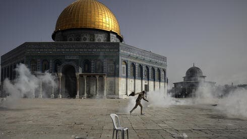 Un palestino huye de los gases lacrimógenos durante los enfrentamientos con las fuerzas de seguridad israelíes frente a la Cúpula de la Roca en el recinto de la mezquita de Al Aqsa.