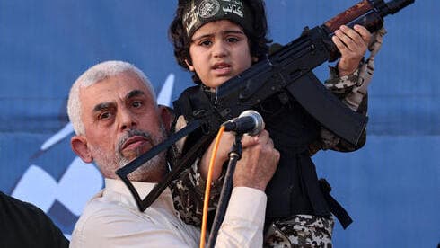 El líder de Hamas, Yahya Sinwar, sostiene al hijo de un combatiente de las Brigadas Al-Qassam, que murió en los recientes enfrentamientos con Israel. 