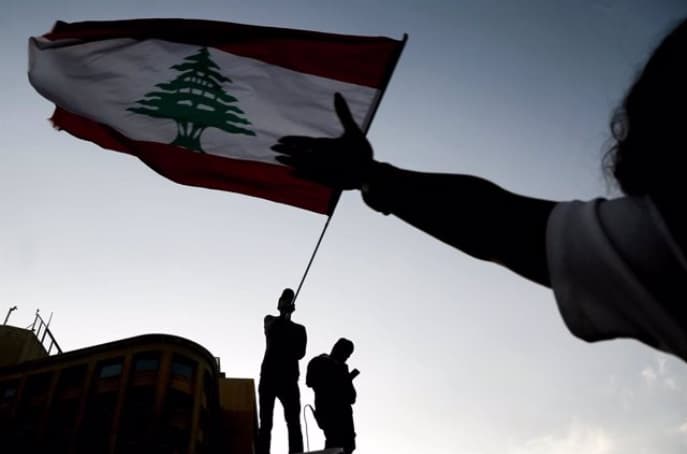Manifestantes ondean la bandera nacional durante una protesta antigubernamental en el centro de Beirut. (AFP) Manifestantes ondean la bandera nacional durante una protesta antigubernamental en el centro de Beirut.