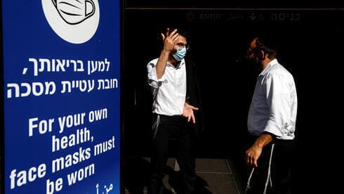 Dos hombres frente a un aviso para extermar cuidados ante el coronavirus, en el aeropuerto internacional Ben Gurión, de Tel Aviv. 