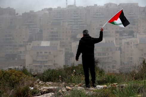 Un manifestante ondea una bandera palestina durante una manifestación cerca del asentamiento de Modi'in Ilit en Cisjordania. 