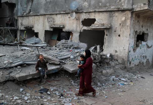 Una mujer palestina con sus hijos observa su casa destruida por los ataques de Israel en mayo. 