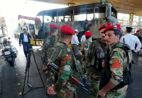 Soldados del ejército sirio cerca del autobús atacado en Damasco.