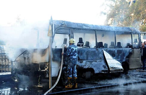 Bomberos apagan el fuego en el autobús militar atacado en Damasco. 