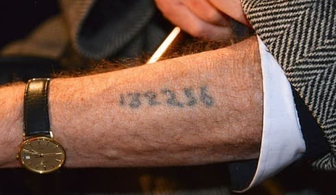 Un sobreviviente del Holocausto muestra un tatuaje del campo de concentración de Auschwitz, en una ceremonia conmemorativa en Estocolmo, Suecia, en 2013. 