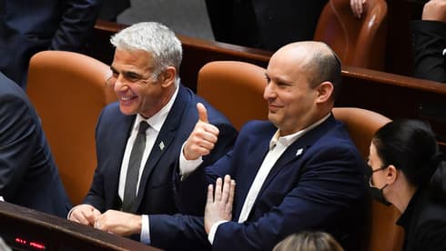 Yair Lapid y Naftalí Bennett, líderes de la coalición de gobierno, celebran la aprobación del presupuesto estatal para 2022. (Yoav Davidkovich) Gantz Lapid Bennett