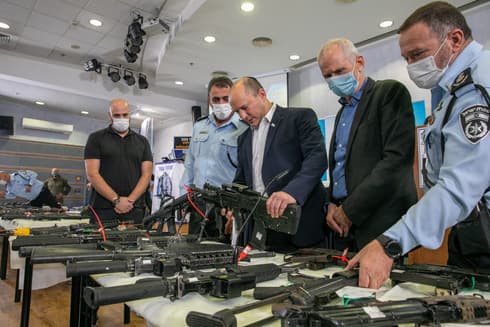 El primer ministro Naftali Bennett observa armas incautadas a delincuentes del sector árabe. (Flash90) El primer ministro Naftali Bennett observa las armas incautadas a delincuentes del sector árabe