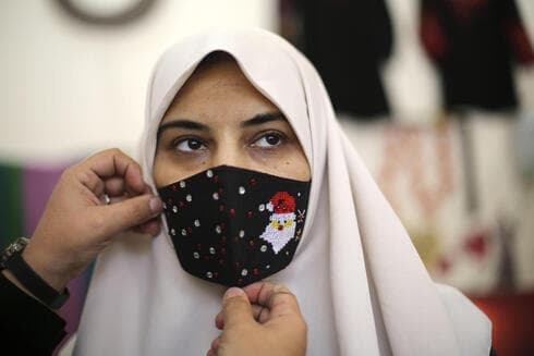 Una mujer palestina prueba una máscara con temática navideña en la ciudad de Gaza. (AP) Una mujer palestina prueba una máscara con temática navideña en la ciudad de Gaza.