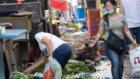  Una mujer busca comida en la basura en el mercado Carmel de Tel Aviv. 