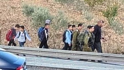 Niños palestinos acompañados por soldados en su camino a la escuela. 