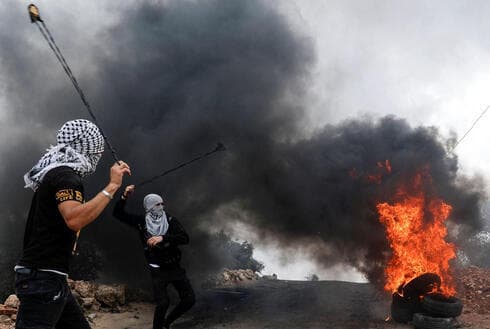 Palestinos lanzan piedras durante una protesta violenca en Cisjordania. 