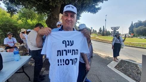 Manifestante de la industria del turismo sosteniendo una camiseta que dice "La industria del turismo está colapsando". ( Meshi Ben Ami) Manifestante de la industria del turismo sosteniendo una camiseta que dice "La industria del turismo está colapsando".