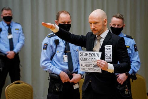 Anders Behring Breivik hace el saludo nazi en la corte durante la audiencia de libertad condicional. "Detengan su genocidio contra nuestras naciones blancas", dice el cartel. (AFP) Anders Behring Breivik hace el saludo nazi en la corte durante la audiencia de libertad condicional.