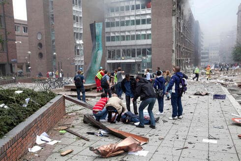 Personas asisten a una víctima de una bomba colocada por Breivik que sacudió Oslo, el 22 de julio de 2011. 