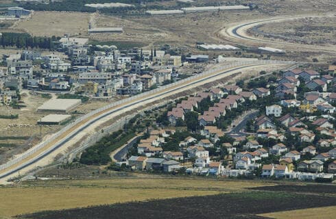 Vista aérea muestra una aldea palestina, a la izquierda, y un asentamiento, a la derecha, separados por el muro de separación en Cisjordania.