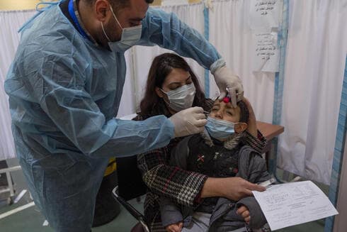 Un trabajador sanitario toma una muestra de hisopo nasal de un niño palestino en un centro de pruebas COVID-19, en la ciudad cisjordana de Ramallah