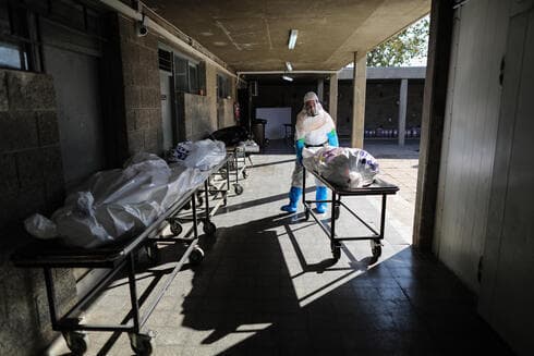 Trabajadores de Chevra Kadisha en trajes de protección preparan los cuerpos de las víctimas de COVID-19 para el entierro. (EPA) Trabajadores de Chevra Kadisha en trajes de protección preparan los cuerpos de las víctimas de COVID-19 para el entierro.