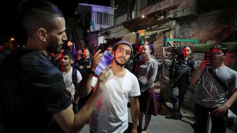 Un residente judío y un manifestante palestino sostienen sus móviles para tomarse fotos el uno al otro en medio de la tensión en curso en Sheikh Jarrah, en mayo de 2021. 
