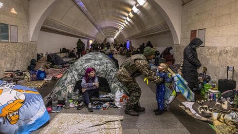 Un soldado ucraniano abraza a su hijo mientras miles de civiles se refugian de los bombardeos rusos en una estación de metro, en Kiev. 