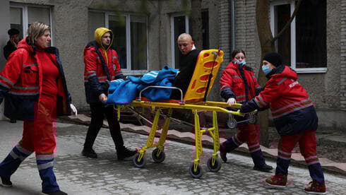 Paramédicos ucranianos trasladan a un herido tras un ataque ruso en una base militar.