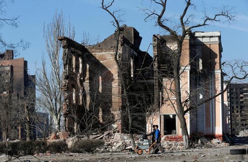 La gente camina junto a los edificios destruidos por los ataques rusos en Mariupol. (Reuters) La gente camina junto a los edificios destruidos por los ataques rusos en Mariupol.