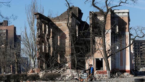 La gente camina junto a los edificios destruidos por los ataques rusos en Mariupol.