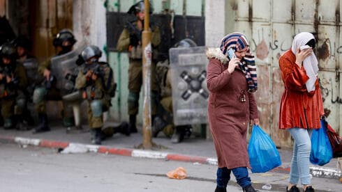 Operativo de las FDI en Cisjordania, mientras dos mujeres palestinas regresan de hacer las compras. (Reuters) Operativo de las FDI en Cisjordania, mientras dos mujeres palestinas regresan de hacer las compras.