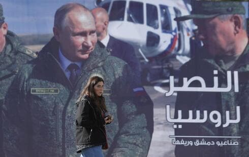 Una mujer pasa junto a una valla publicitaria que muestra al presidente ruso Vladimir Putin en Damasco. (AP) Una mujer pasa junto a una valla publicitaria que muestra al presidente ruso Vladimir Putin en Damasco.