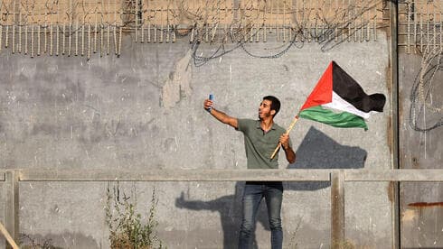 Manifestante palestino levanta una bandera nacional cerca de la valla fronteriza de Israel. (AFP) Manifestante palestino levanta una bandera nacional cerca de la valla fronteriza de Israel.