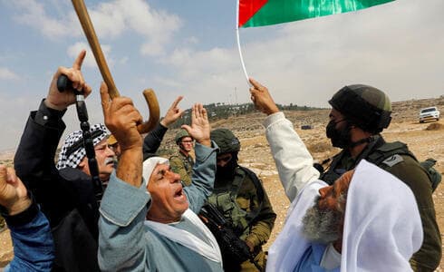 Manifestantes palestinos gesticulan junto a las fuerzas israelíes durante una protesta contra los asentamientos israelíes en Masafer Yatta, en Cisjordania, el 2 de octubre de 2021. (Reuters) Manifestantes palestinos gesticulan junto a las fuerzas israelíes durante una protesta contra los asentamientos israelíes en Masafer Yatta, en Cisjordania, el 2 de octubre de 2021.
