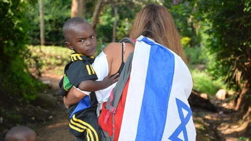 Una voluntaria atiende a un huerfanito envuelta en una bandera de Israel. (Gentileza) Una voluntaria atiende a un huerfanito envuelta en una bandera de Israel.