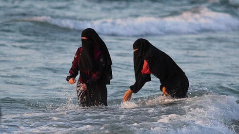 Mujeres de Gaza disfrutan de las olas en la orilla del mar.