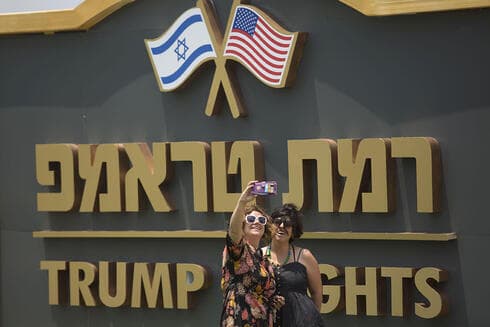 Dos mujeres se hacen una foto contra un cartel a la entrada de Trump Heights. 