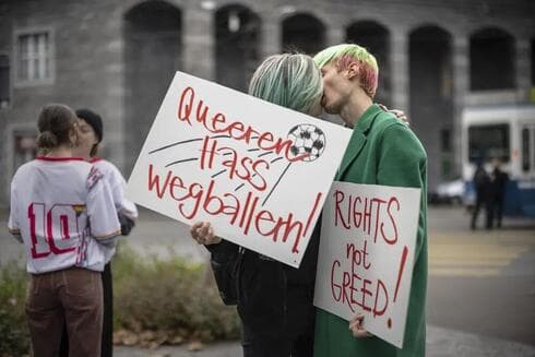 Manifestantes se besan mientras sostienen pancartas que dicen "Dispara odio queer" y "Derechos no codicia" durante una manifestación sobe los derechos humanos de las personas LGBTQ en Catar y la responsabilidad de la FIFA. (AP) Manifestantes se besan mientras sostienen pancartas que dicen "Dispara odio queer" y "Derechos no codicia" durante una manifestación sobe los derechos humanos de las personas LGBTQ en Catar y la responsabilidad de la FIFA.