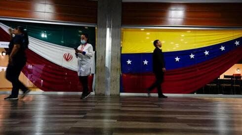 Varias personas pasean junto a las banderas nacionales de Irán (izquierda) y Venezuela en Caracas, Venezuela. (AP) Varias personas pasean junto a las banderas nacionales de Irán (izquierda) y Venezuela en Caracas, Venezuela.