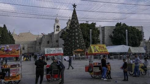 Vendedores palestinos esperan a los clientes junto al árbol de Navidad en la Plaza del Pesebre, junto a la Iglesia de la Natividad, tradicionalmente considerada por los cristianos como el lugar de nacimiento de Jesucristo, antes de Navidad, en la ciudad cisjordana de Belén, el lunes 5 de diciembre de 2022. (AP) Vendedores palestinos esperan a los clientes junto al árbol de Navidad en la Plaza del Pesebre, junto a la Iglesia de la Natividad, tradicionalmente considerada por los cristianos como el lugar de nacimiento de Jesucristo, antes de Navidad, en la ciudad cisjordana de Belén, el lunes 5 de diciembre de 2022.