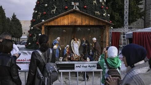 La gente toma fotos del árbol de Navidad y el belén en la Plaza del Pesebre, fuera de la Iglesia de la Natividad, tradicionalmente creída por los cristianos como el lugar de nacimiento de Jesucristo, antes de Navidad, en la ciudad cisjordana de Belén, el lunes 5 de diciembre de 2022. (AP) La gente toma fotos del árbol de Navidad y el belén en la Plaza del Pesebre, fuera de la Iglesia de la Natividad, tradicionalmente creída por los cristianos como el lugar de nacimiento de Jesucristo, antes de Navidad, en la ciudad cisjordana de Belén, el lunes 5 de diciembre de 2022.