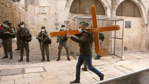 Un cristiano lleva una cruz a lo largo de la Vía Dolorosa antes de la procesión del Viernes Santo en la Ciudad Vieja de Jerusalem. (AP) Un cristiano lleva una cruz a lo largo de la Vía Dolorosa antes de la procesión del Viernes Santo en la Ciudad Vieja de Jerusalem.