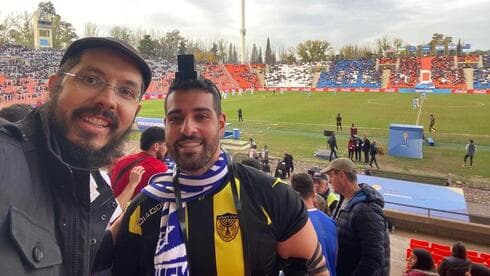 Ayuda a un aficionado israelí para ponerse tefilín en las gradas. 