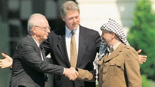 Isaac Rabin, Yasser Arafat y Bill Clinton durante la firma de los Acuerdos de Oslo. (AFP) El primer ministro Yitzhak Rabin y el líder palestino Yasser Arafat se dan la mano en la ceremonia de firma de los Acuerdos de Oslo en la Casa Blanca; en el centro: El presidente de EE.UU. Bill Clinton.