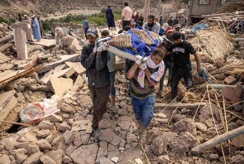 Varias personas transportan los restos de una víctima del terremoto.